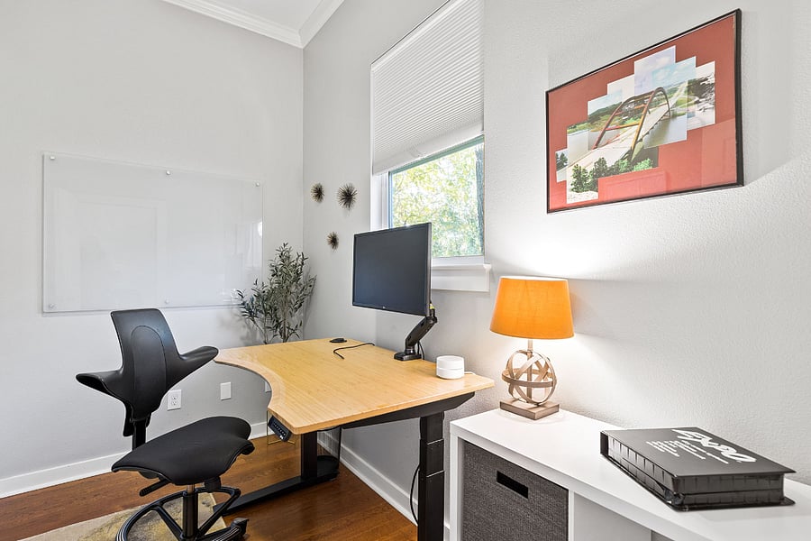 Dedicated office space with white board, monitor, standing desk, and a view of the backyard