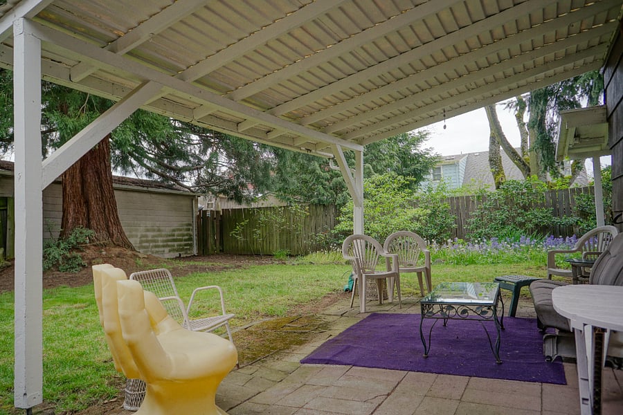 Spacious fenced in backyard with covered patio and enormous redwood tree