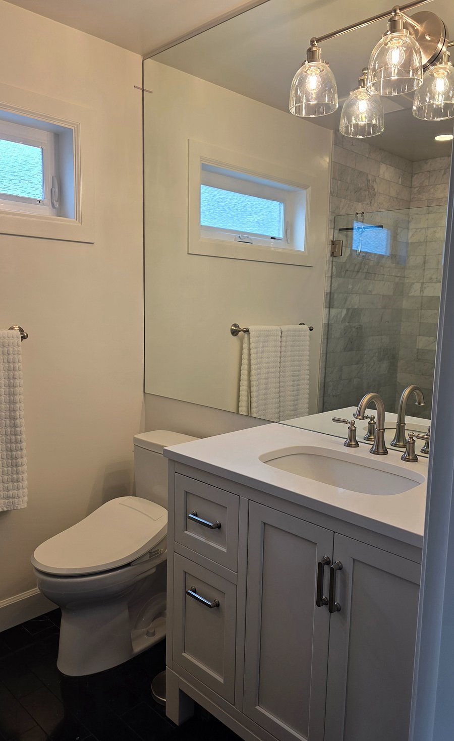 View of bathroom sink, bidet toilet, and wall to ceiling mirror. 