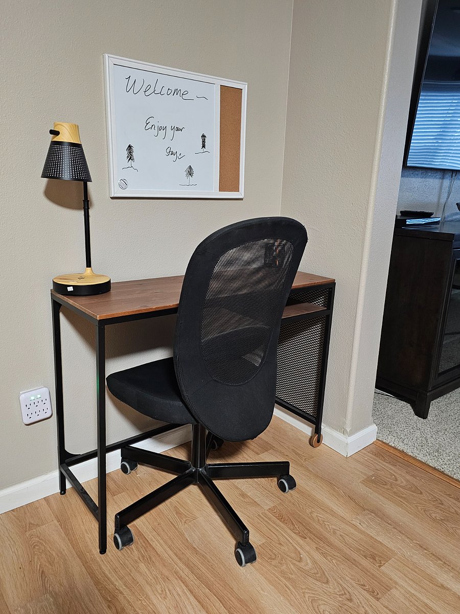 Desk space with ergonomic chair, white board and a phone charging lamp.