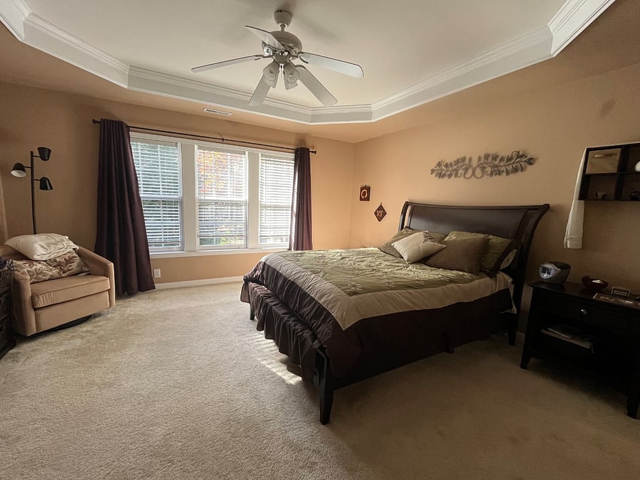Large primary bedroom with trey ceiling and sitting area.