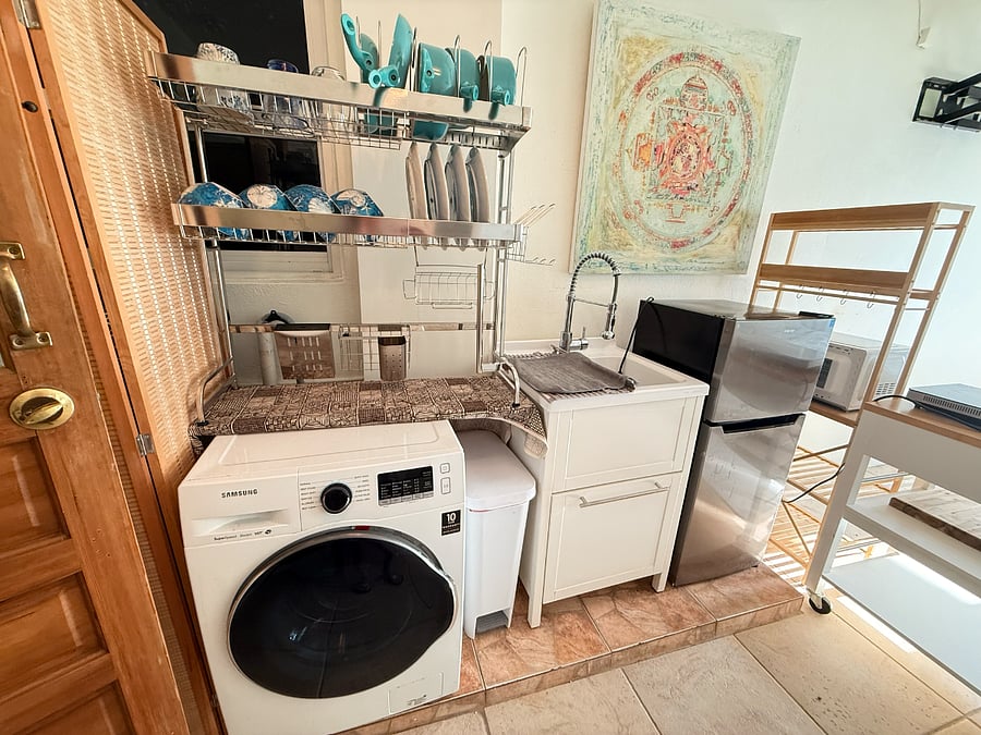 Kitchenette complete with refrigerator, bakers rack, 2 burner induction stovetop, space saving Ninja air fryer/toaster oven combination and beach inspired dinnerware as well as ceramic pots and pans.