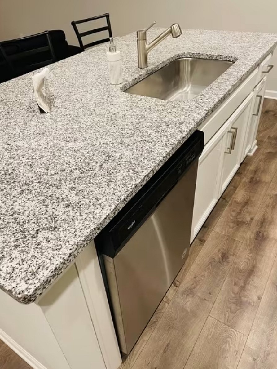 Kitchen island is equipped with a large sink, sprayer faucet and dishwasher

