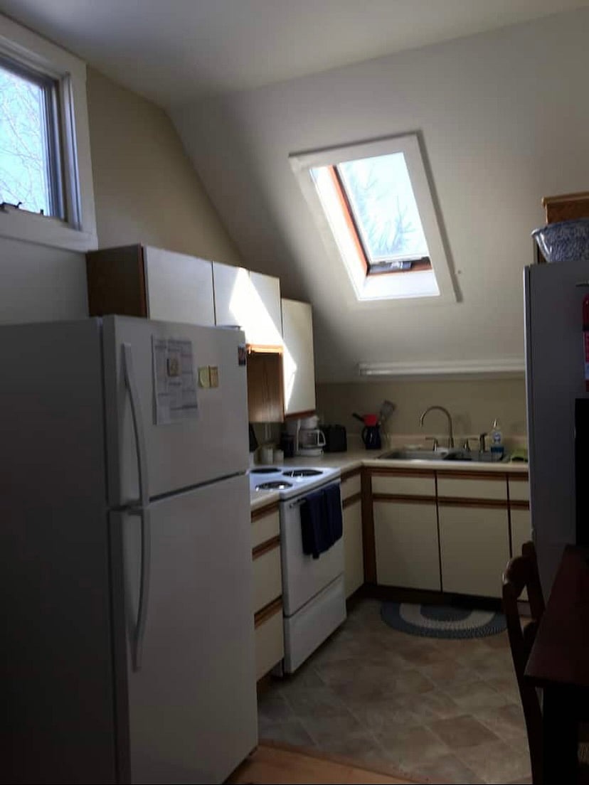 Efficient kitchen with skylight, electric stove, microwave, full-size refrigerator, double sinks, coffeemaker, toaster.