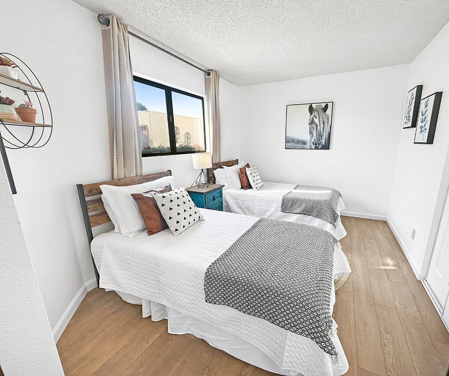 This third bedroom features two comfortable twin-size beds, each topped with soft linens and plush pillows to ensure a restful nights sleep. The room includes a spacious closet, nightstand with lamp, and blackout curtains.