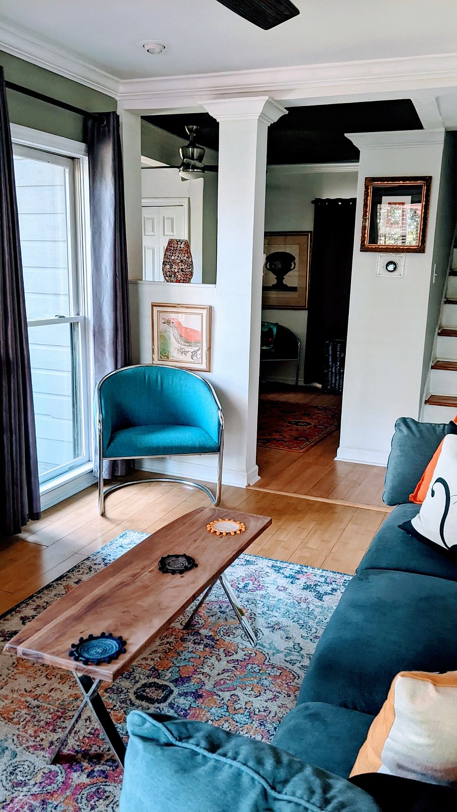 mid century chair in the livingroom with view of the stairs leading to the upstairs bathroom and kitchenel