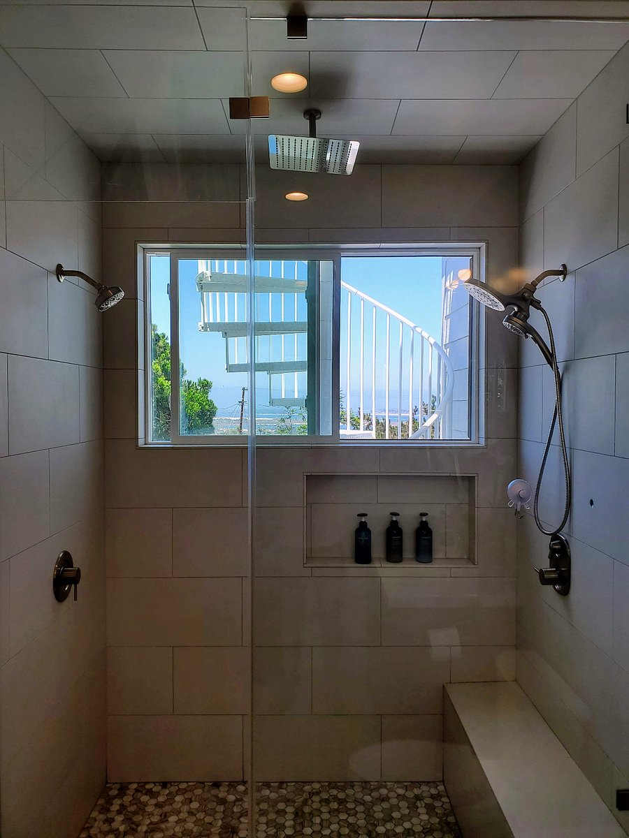 Luxury walk-in shower with bench seat, 4 shower heads, and bay/ocean view