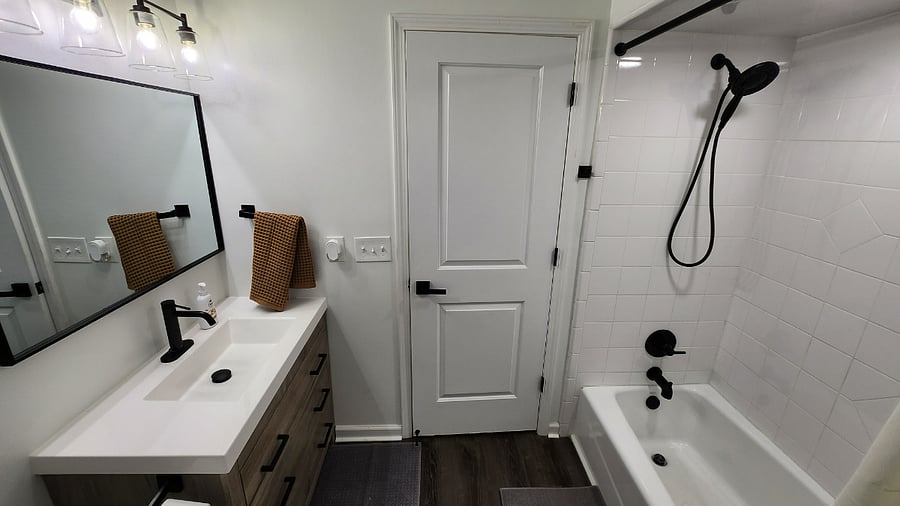 Bathroom 1st view with hand held shower head and oversized vanity mirror.