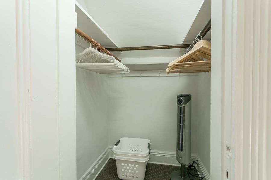 Walk-in closet in bedroom, includes laundry baskets & tower fan