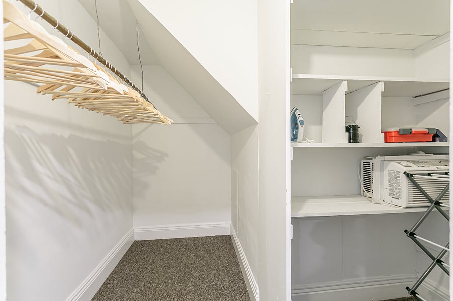 Walk-in closet in foyer with built-in shelving, first-aid kit, AC window unit, full size ironing board, iron, clothes drying rack