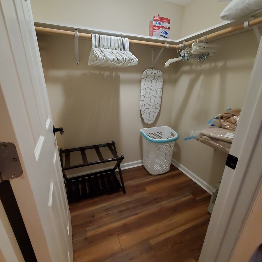 Walk-in closet with hangers, laundry basket, box fan, space heater, ironing board & iron and extra blankets