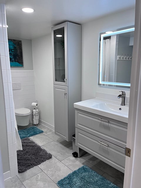 Full size bathroom with anti-fog mirror, storage, soaking tub and rain shower