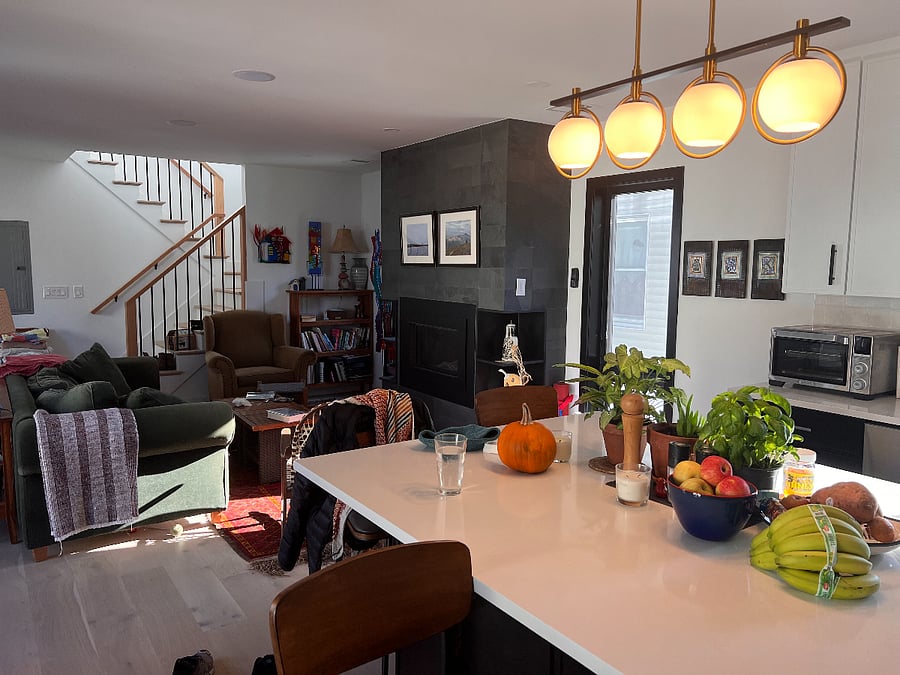Kitchen island with living room and stairs leading upstairs in background. 