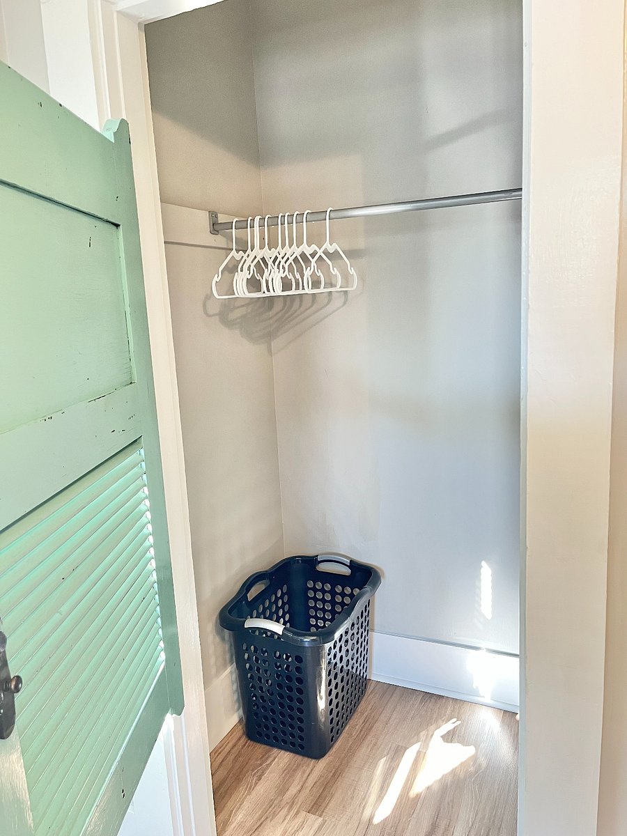 Interior of bedroom closet with hangers and hamper.