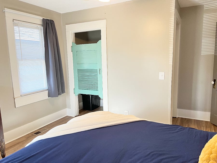 Roomy front bedroom closet with vintage door and full blackout curtains.