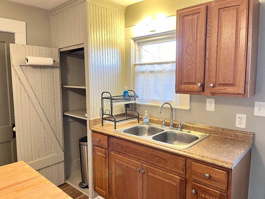 A view into the pantry with large lidded garbage can.