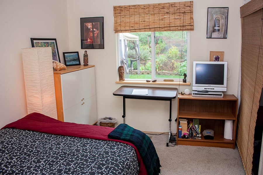A second bedroom with queen bed with a big window view of the garden