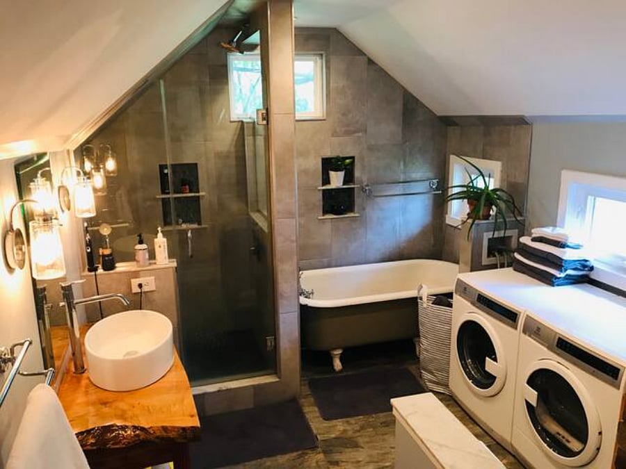 bathroom with newly reglazed clawfoot tub, washer, dryer, ironing board, hair dryer, shower with rain head and stone floor