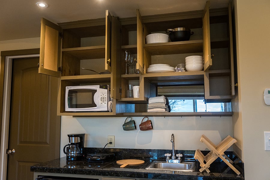 Kitchenette with microwave, induction hot plate, coffee maker, and kitchen basics (plates, bowls, glasses)