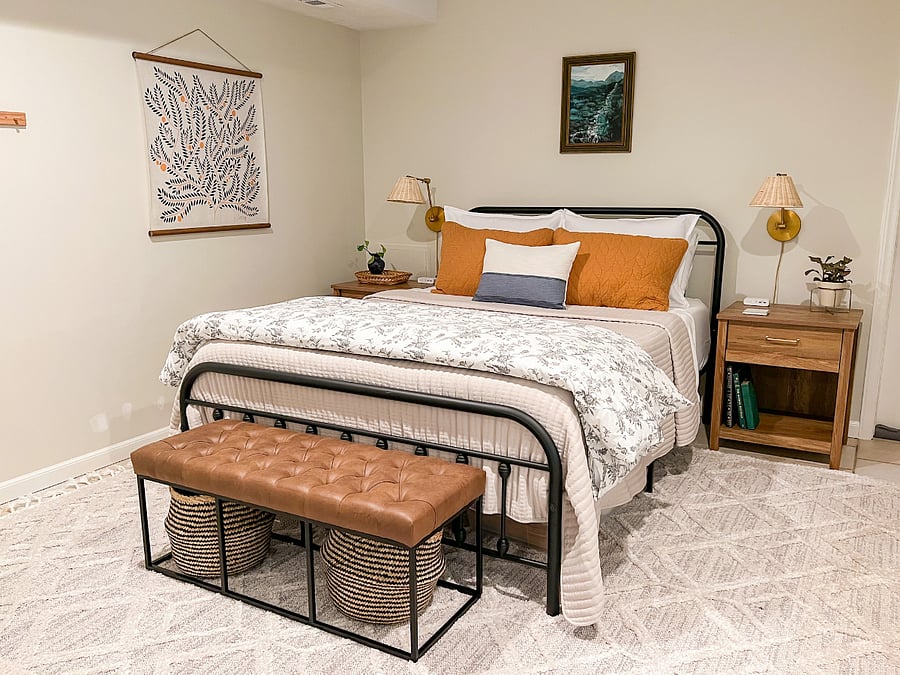 Cozy bedroom with queen bed and two nightstands with ambient lighting and charging stations. There's also a wall rack to hang additional items.