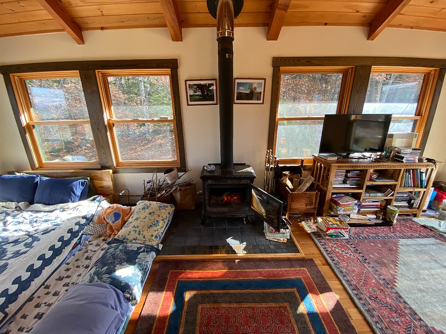 Living area with TV, seating area and extra bed to lounge on next to fireplace
