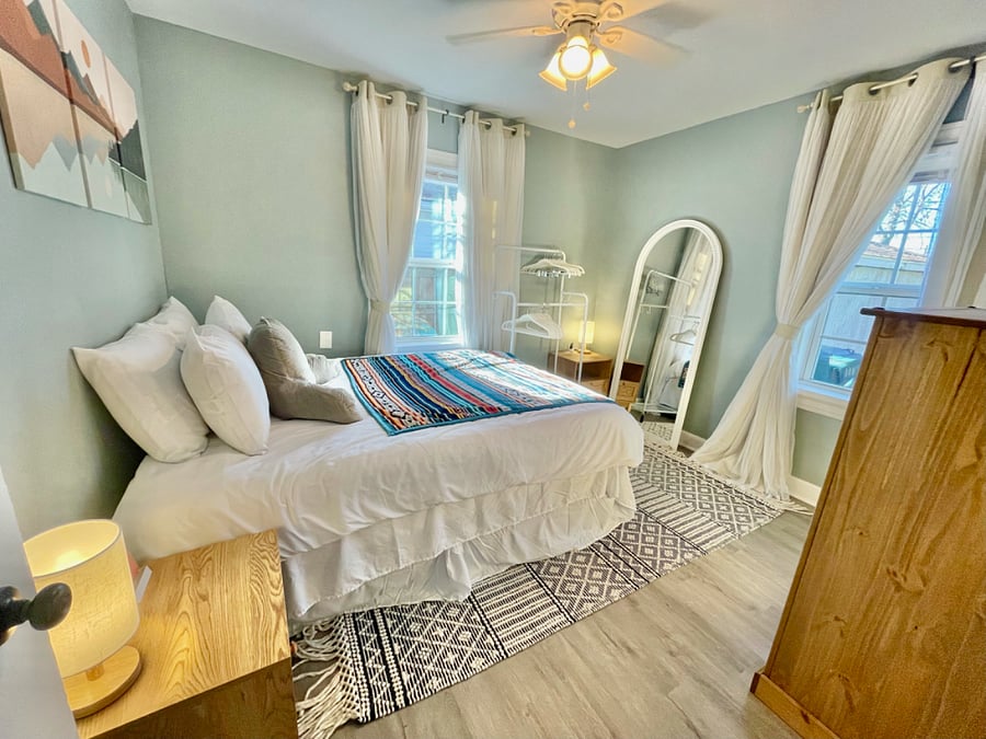 Light, airy, boho-styled bedroom. Room darkens fully with blinds/curtains drawn.