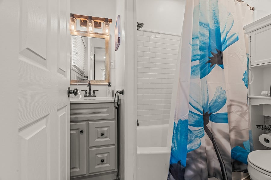 Back porch full bathroom with tub: our bathrooms all follow the floral art theme. This bathroom is accessible to all or can be converted into an en-suite if you wish to lock the mud room & make it a fourth bedroom for your stay