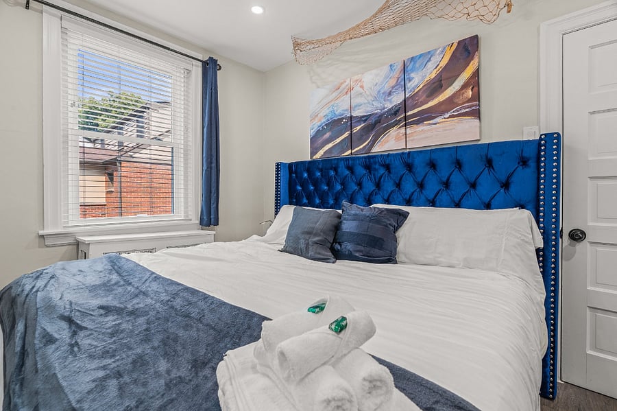 Spacious king size beds in each bedroom: this one features a blue velvet bed against a backdrop of a beach underneath a ceiling mounted fishing net - along with a closet, you can enjoy your own private glass office study desk and ergonomic chair!