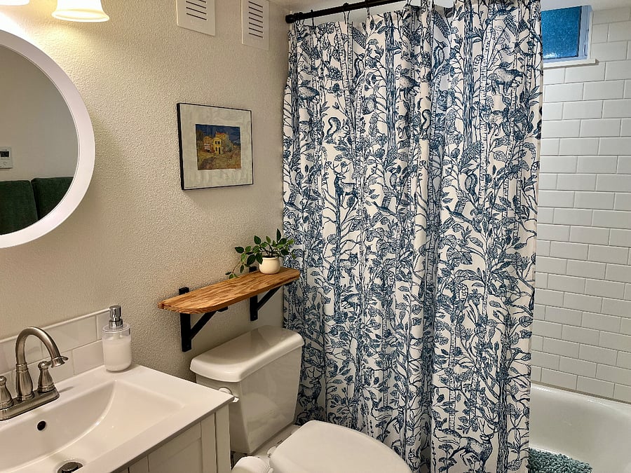 Bright, clean bathroom with full-sized bathtub, shower and essentials like body wash, shampoo and conditioner