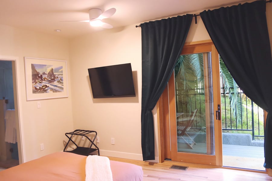 Bedroom with smart TV, blackout curtains, door to private deck.