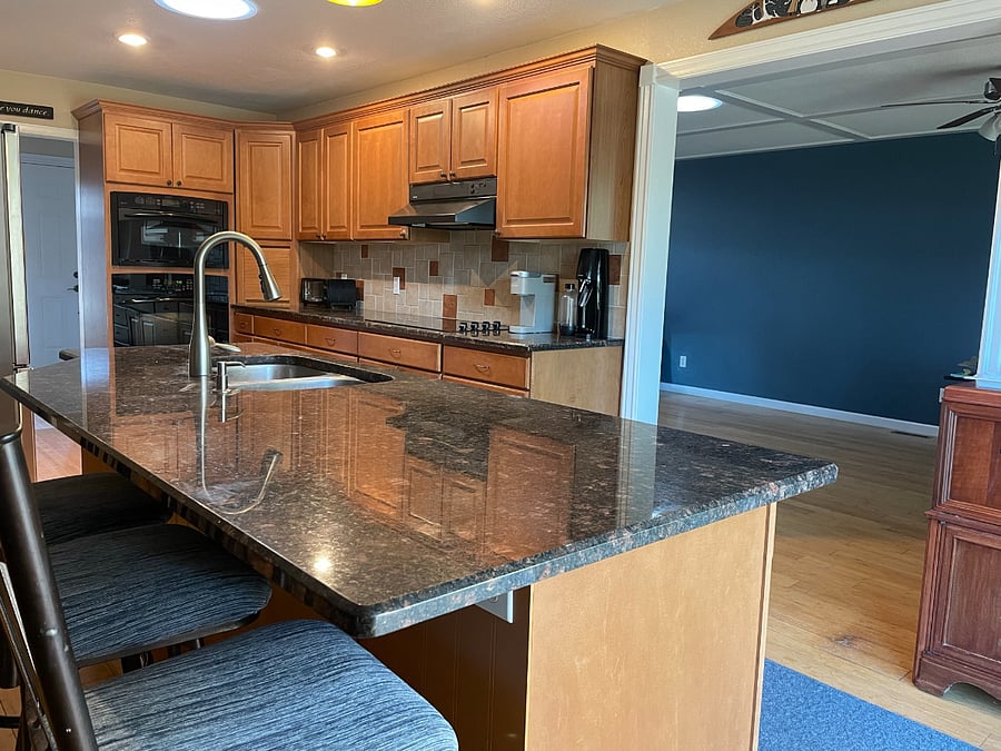 Kitchen with full-sized fridge, oven, microwave, range, island, and bar stools.