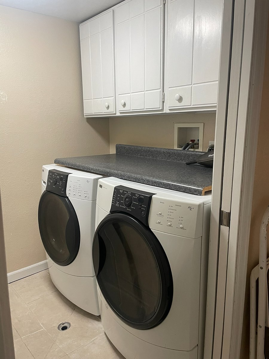 Laundry room (downstairs) with front-loading washer and dryer, utility sink, and storage.