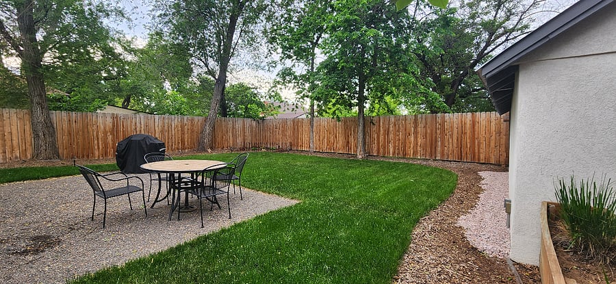 Backyard shared space includes a table with chairs and access to a grill.