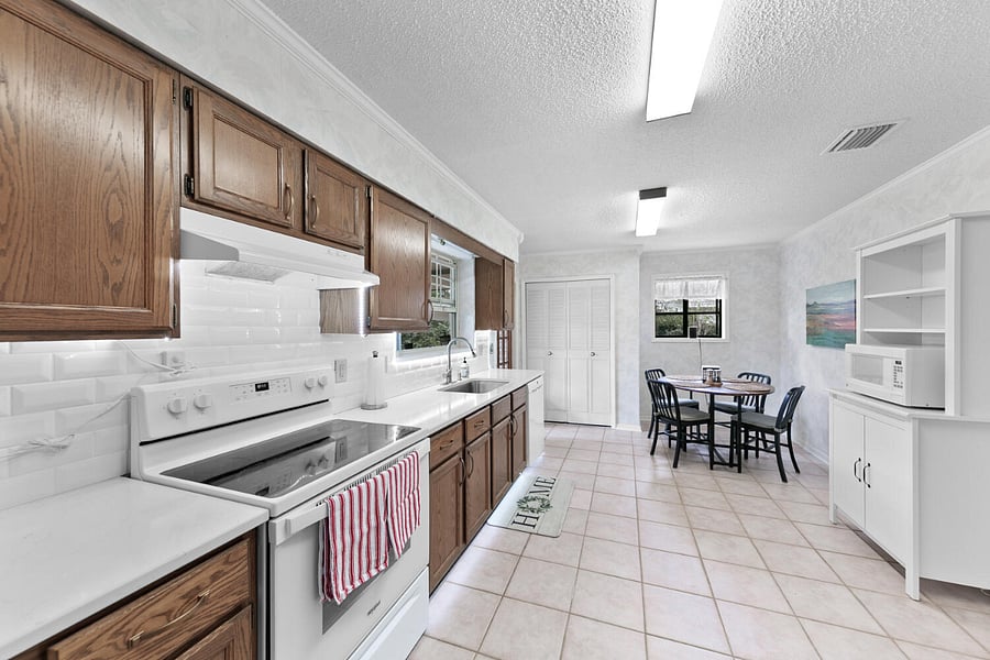 Updated kitchen includes oak cabinets with new hardware, new quartz countertops, newly installed subway tile backsplash, and new large undermount double bowl sink