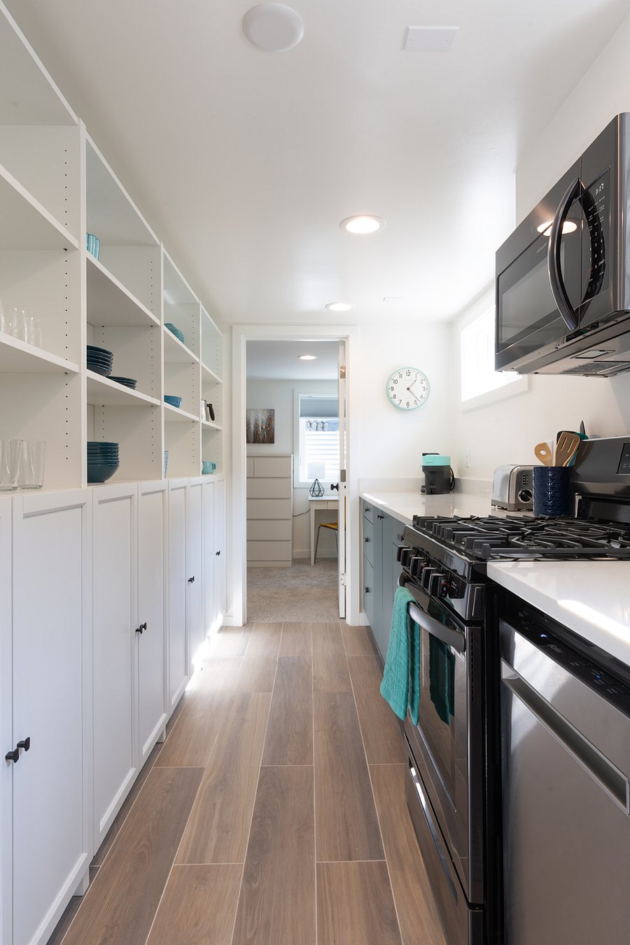 View through kitchen to bedroom at rear of apartment. Lots of storage in cabinets on wall. Full size gas range and oven, built in microwave.