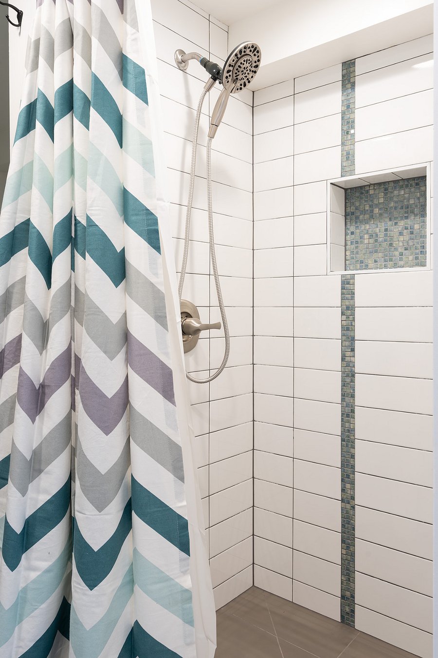 Shower with removable wand and shampoo storage nook.