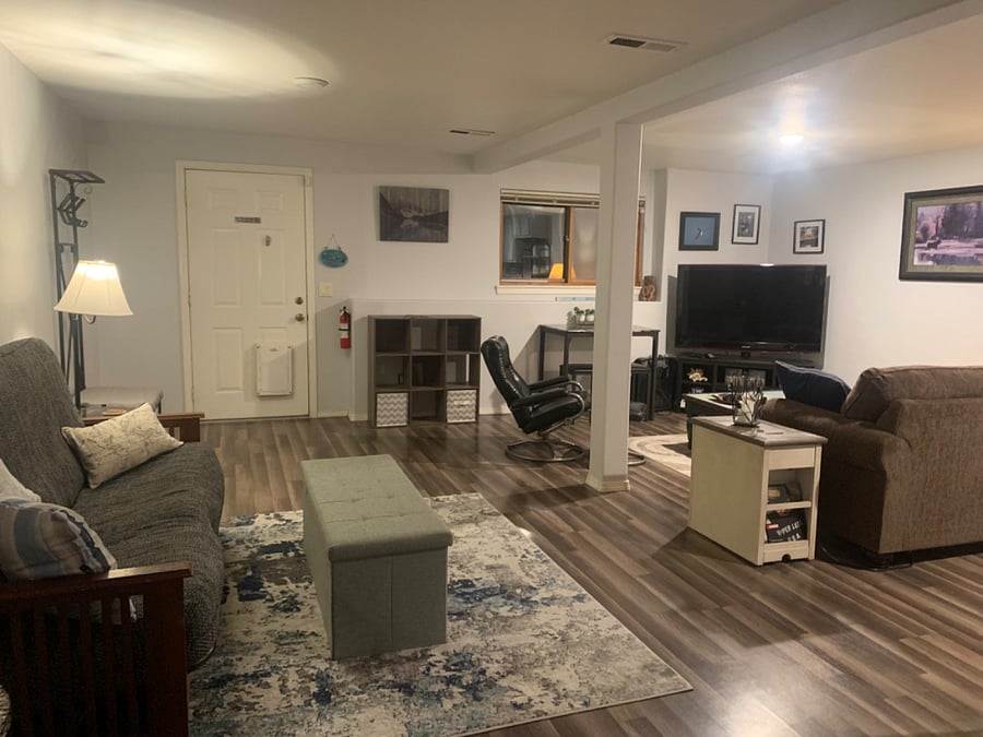 Large open area for living, including futon, love seat, cafe table, chair, ottoman, TV, coffee table and cube storage