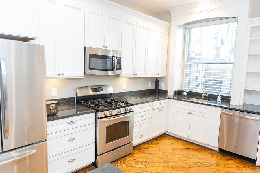 The kitchen with lots of cabinet space, dishes, pots, pans, gas stove, large refrigerator, microwave and lots of light from outside. 
