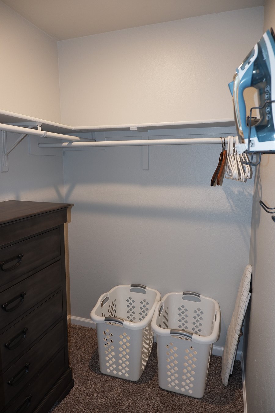 Spacious closet including dresser, iron and ironing board.