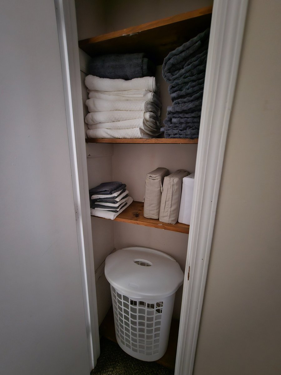 Linen closet with extra sheets, towels & laundry basket