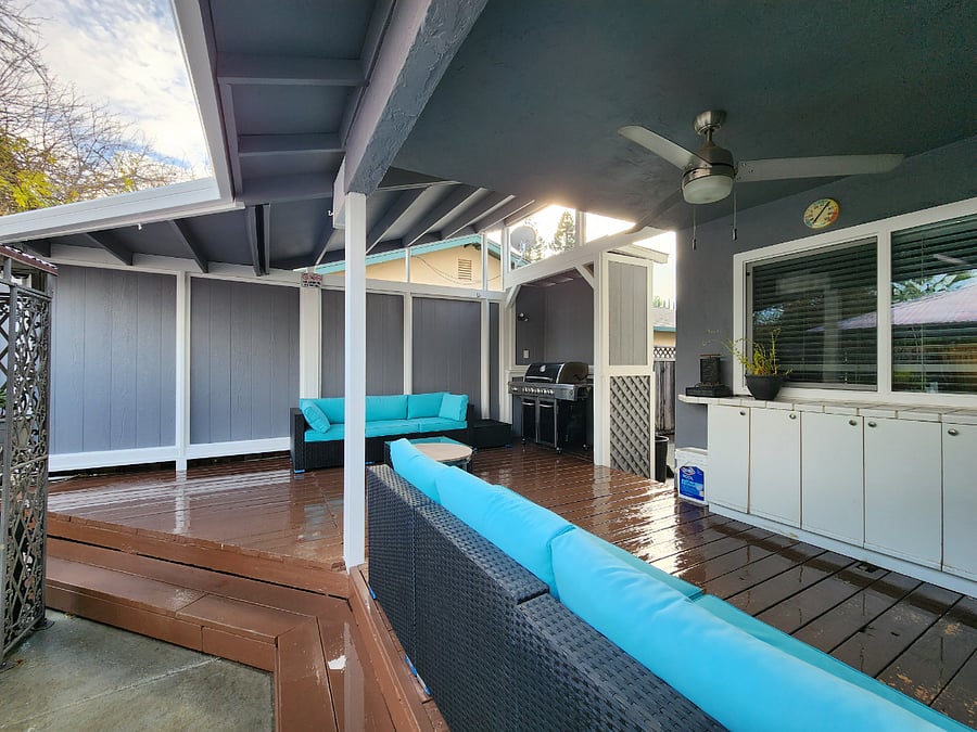 Backyard covered deck with BBQ grill, and couches. 