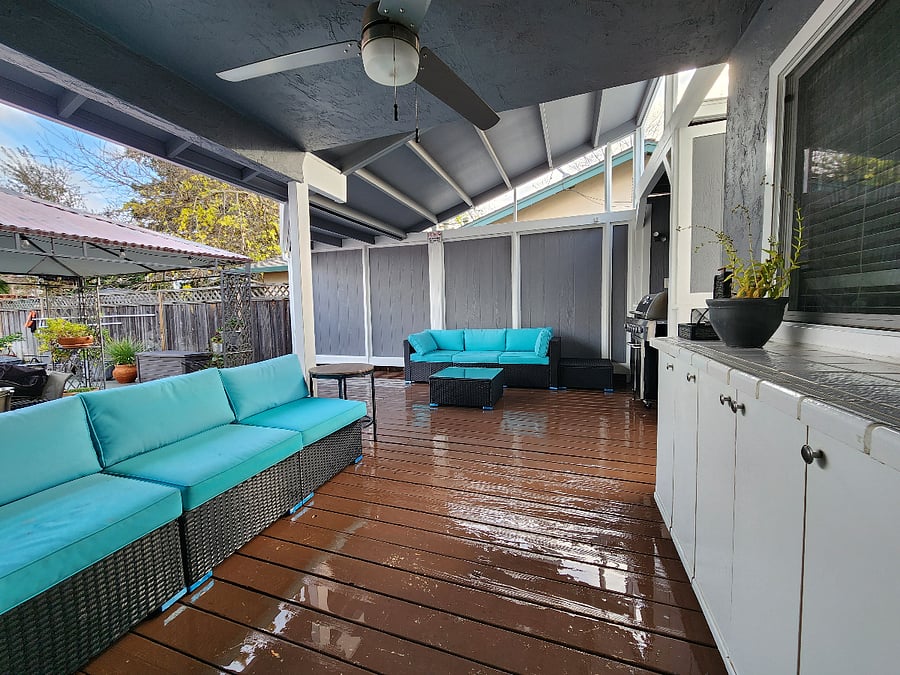 Backyard covered deck with BBQ grill, and couches.