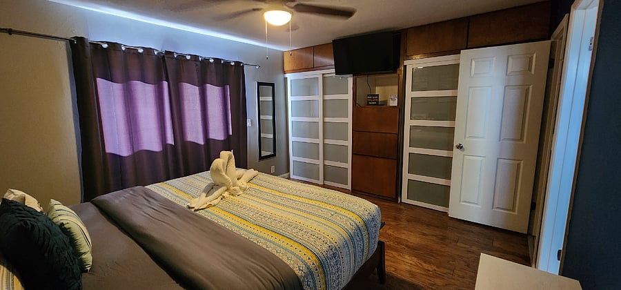 Bedroom #1 - King size bed, smart TV, ceiling fan, desk (workspace), dresser, two full size closets, private bathroom, and sliding door leading to backyard with pool and hot tub.