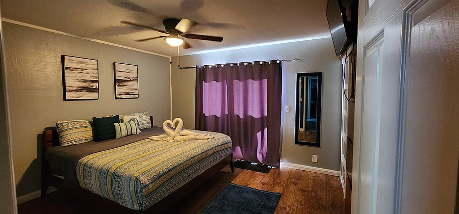 Bedroom #1 - King size bed, smart TV, ceiling fan, desk (workspace), dresser, two full size closets, private bathroom, and sliding door leading to backyard with pool and hot tub.