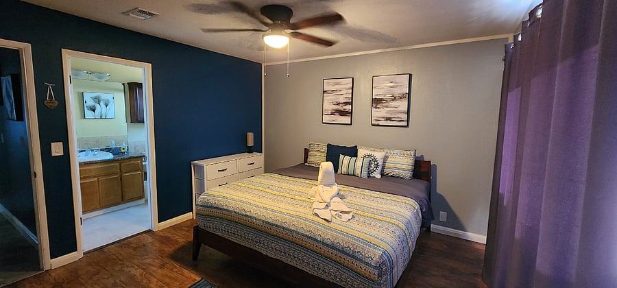 Bedroom #1 - King size bed, smart TV, ceiling fan, desk (workspace), dresser, two full size closets, private bathroom, and sliding door leading to backyard with pool and hot tub.