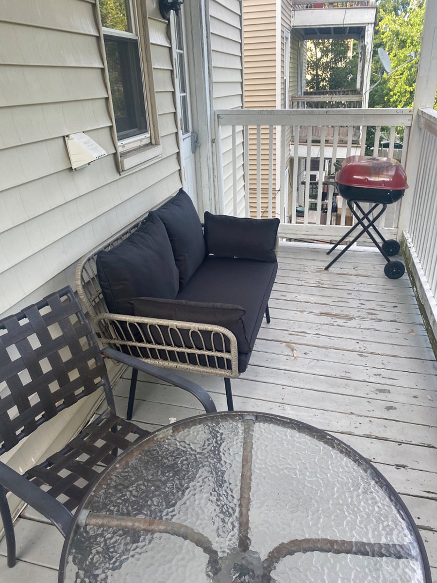 Back porch with charcoal grill, loveseat, and dining area.