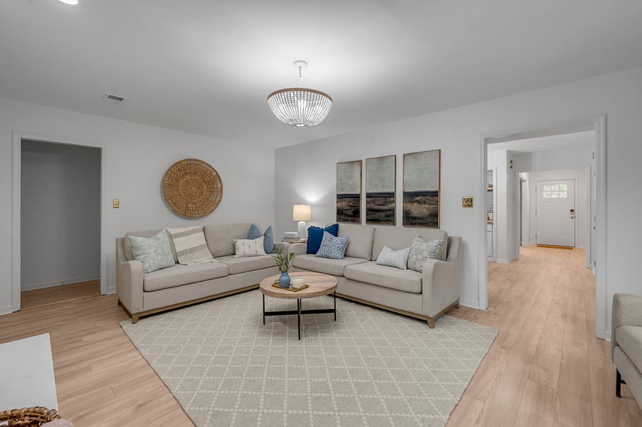 Cuddle couches in the living room with view into kitchen entryway on the right and entryway from garage on the left of photo.