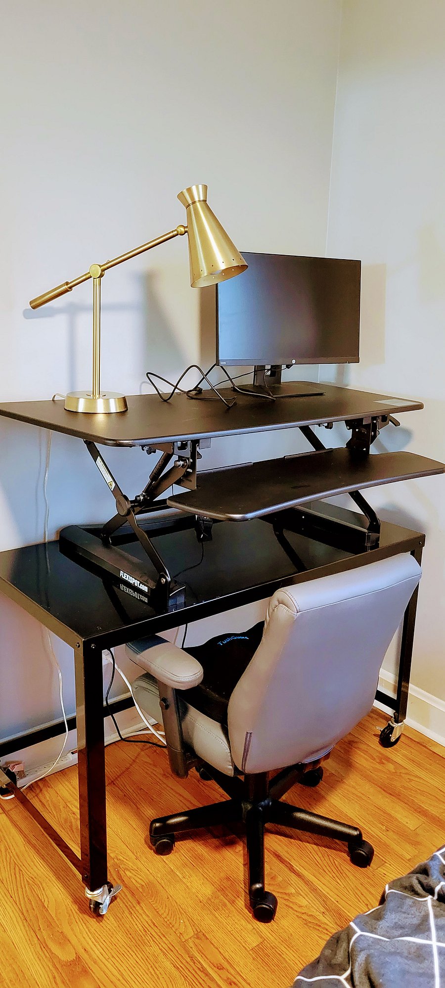Work station includes an adjustable sit/stand desk, monitor, hdmi cable, desk lamp, and office chair with chair pad.