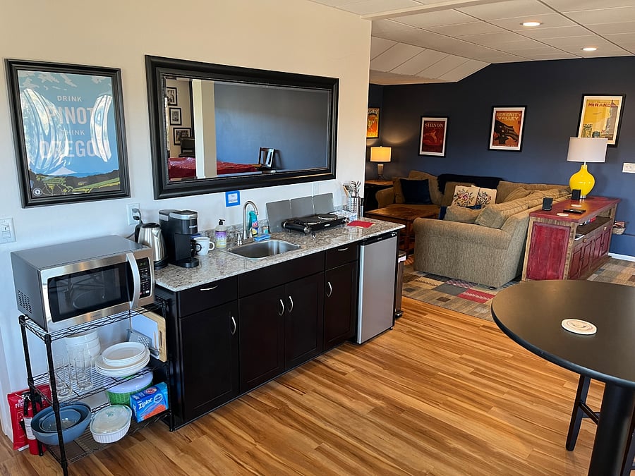 Wet bar equipped with mini-fridge, microwave, Keurig, hot plate, and tea kettle.