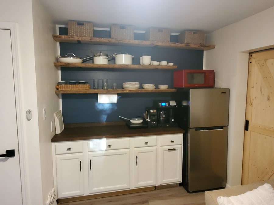 Kitchenette with open shelving and plenty of dinnerware.